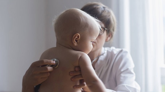 Eine Kinderärztin untersucht einen kleinen Jungen in einer Klinik. Bei den regelmäßigen Früherkennungsuntersuchungen (U1-U9) sprechen Ärzte mit den Eltern auch über anstehende Impfungen.