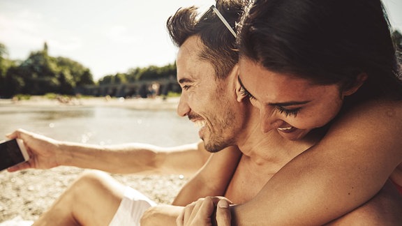 Verliebtes Paar macht am Strand Selfies