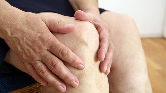 Ein Patient hält sich das schmerzende Knie.