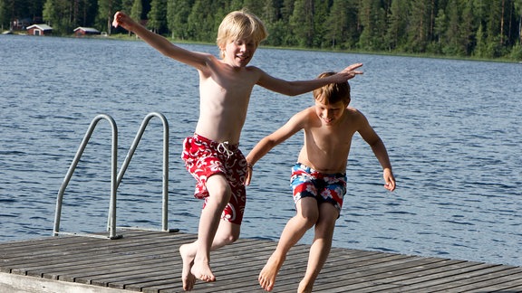 Zwei Kinder springen in einem See