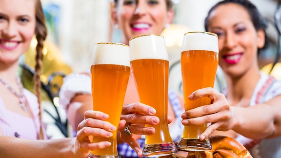 Drei Frauen stoßen mit Bier an.
