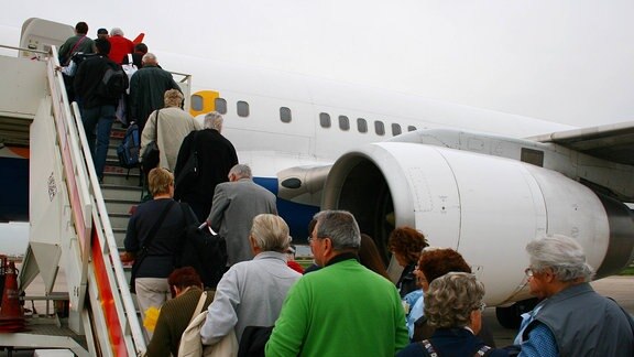 Ohne Tunnel: Urlauber steigen in ein Flugzeug ein