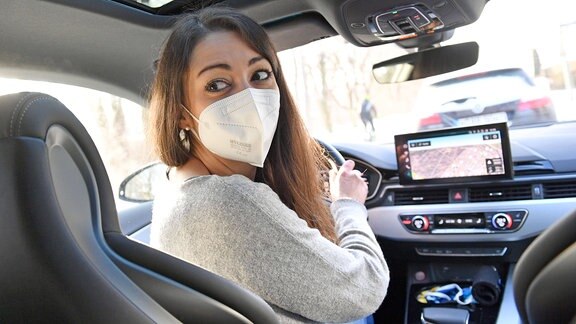 Frau trägt Maske beim Autofahren
