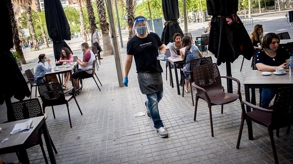 Ein Kellner mit Mundschutz in einem Straßencafé