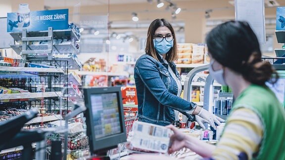 Kundin mit Mund-Nasen-Schutz an einer Supermarkt-Kasse