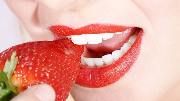 Eine Frau beißt in eine Erdbeere
