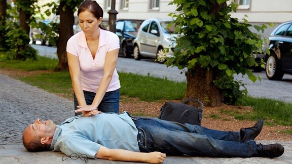 Junge Frau macht eine Herzdruckmassage bei einem Mann