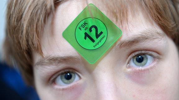 Ein Teenager mit einem FSK-Aufkleber auf der Stirn