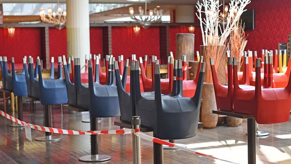 Gestapelte Stühle auf Tischen eines Gastronomiebetriebes