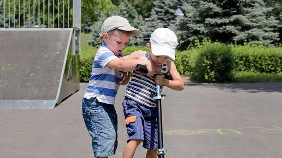 Zwei Kinder streiten um einen Roller