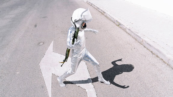 Junge, der Astronautenkostüm trägt, das auf Straße in der Stadt geht