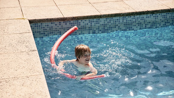 Junge mit Schwimmhilfe im Becken
