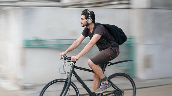 Mann fährt Rad mit Kopfhörern im Ohr