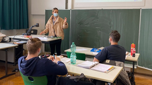 Lehrer und Schüler mit Maske im Unterricht