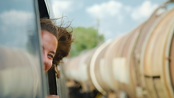 Mädchen schaut während der Fahrt aus dem Zugfenster (Symbobild)
