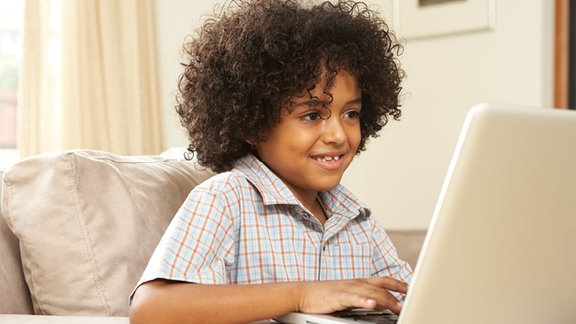 Ein Junge sitzt an einem Laptop.