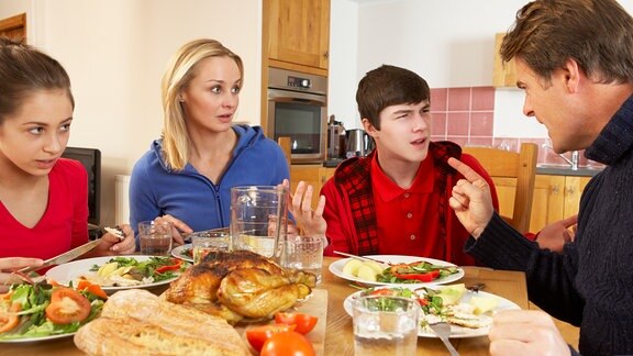 Eine Familie diskutiert am Essenstisch.