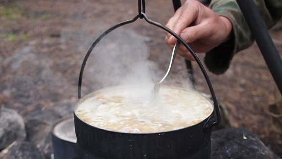 Eine Suppe kocht in einem Topf über offenem Feuer