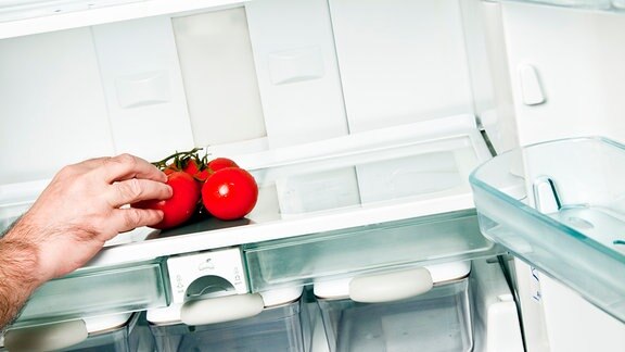 Ein Mann legt Tomaten in den Kühlschrank