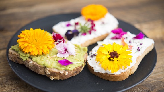 Toast mit Avocado-Hummus und Sprad-Käse mit essbaren Blüten