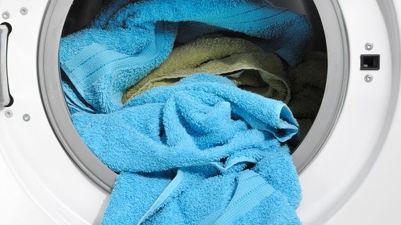 Aus einer Waschmaschine hängt Wäsche