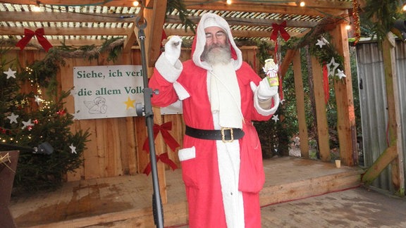 Ein Mensch in einem Weihnachtsmann-Kostüm steht in einem Unterstand.